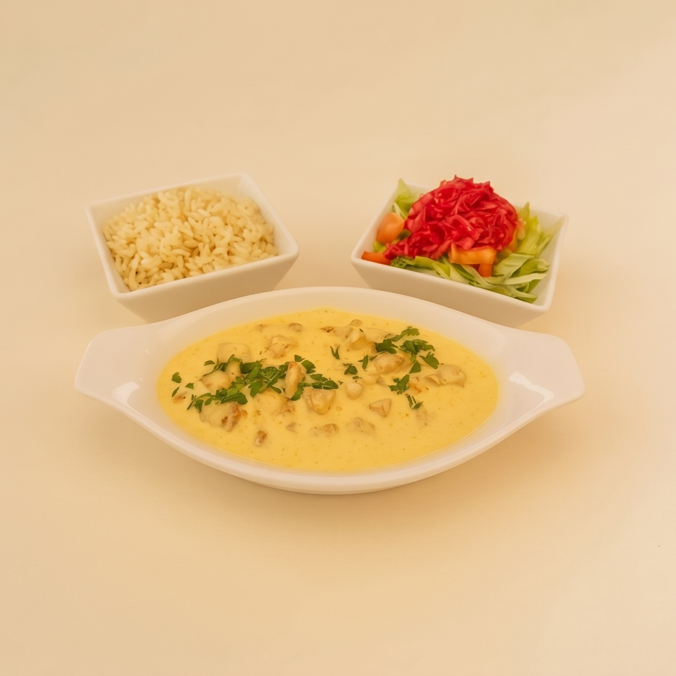 Creamy herb-garnished chicken dish served with rice and a fresh salad in white bowls.